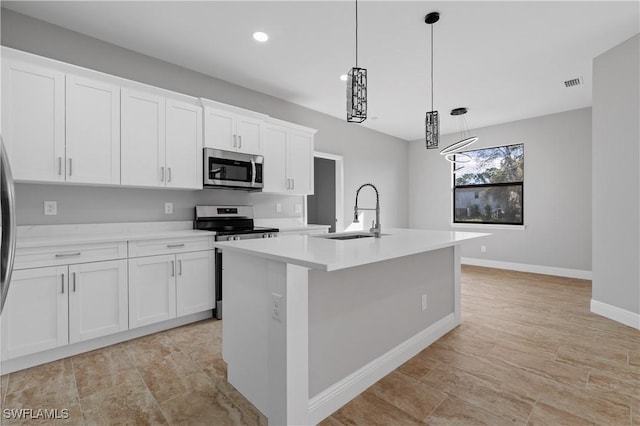 kitchen featuring a kitchen island with sink, stainless steel appliances, a sink, white cabinetry, and light countertops