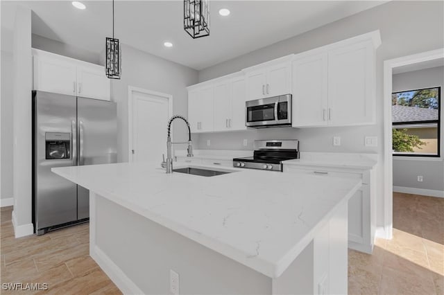 kitchen with a center island with sink, white cabinets, hanging light fixtures, stainless steel appliances, and a sink