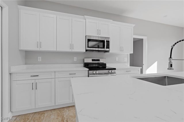 kitchen with appliances with stainless steel finishes, white cabinets, and a sink