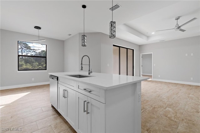 kitchen featuring light countertops, a kitchen island with sink, a sink, and hanging light fixtures