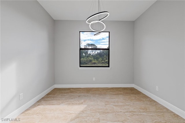 empty room with baseboards and a notable chandelier