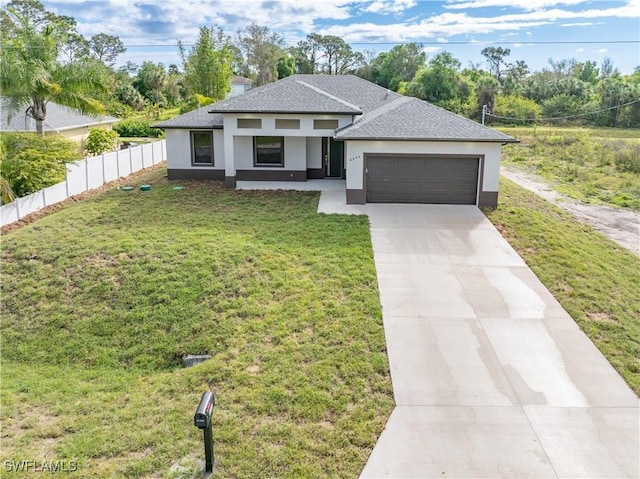 prairie-style house with a garage, concrete driveway, a front yard, and fence