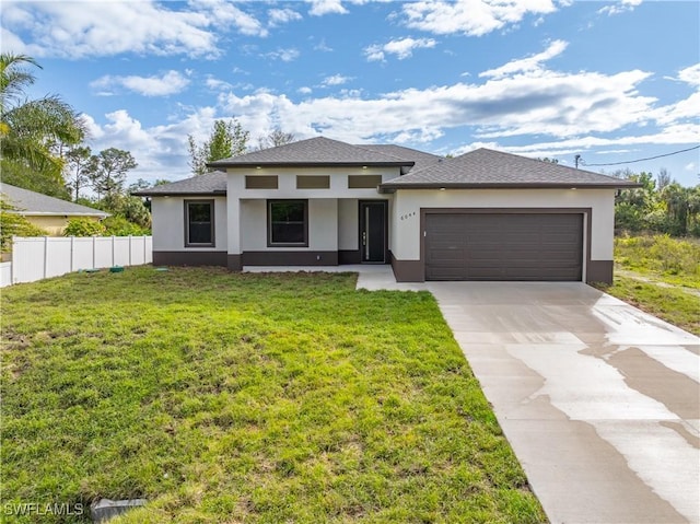 prairie-style home featuring a garage, fence, a front lawn, and concrete driveway