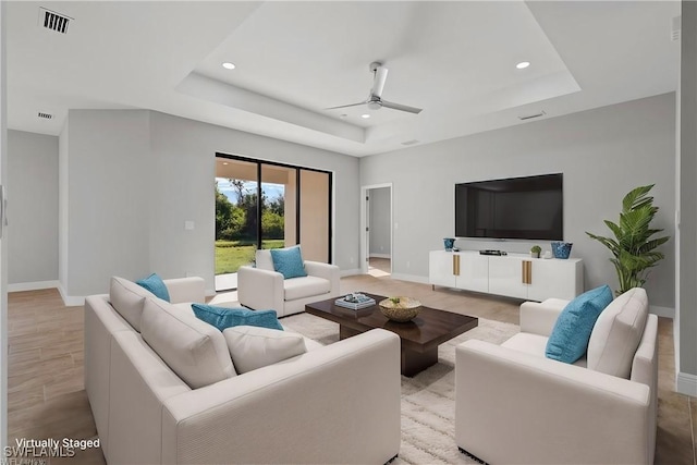 living room featuring baseboards, a tray ceiling, and recessed lighting