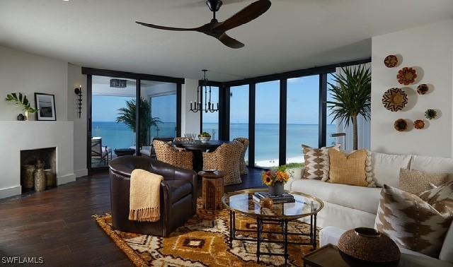 living room with expansive windows, dark wood-type flooring, a water view, and a fireplace