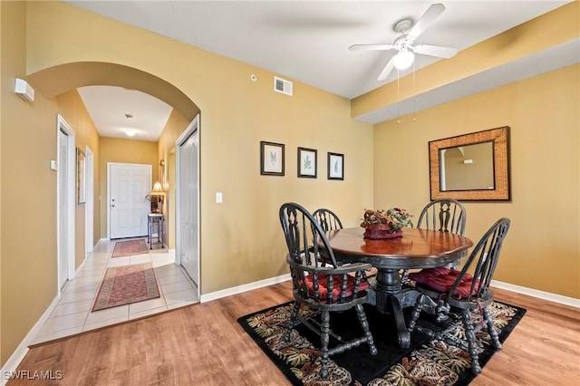 dining area featuring arched walkways, light wood-style flooring, visible vents, and baseboards