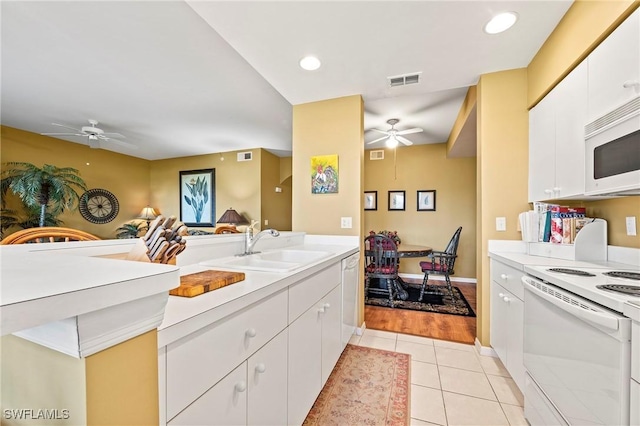 kitchen with light countertops, light tile patterned flooring, a sink, white cabinets, and white appliances