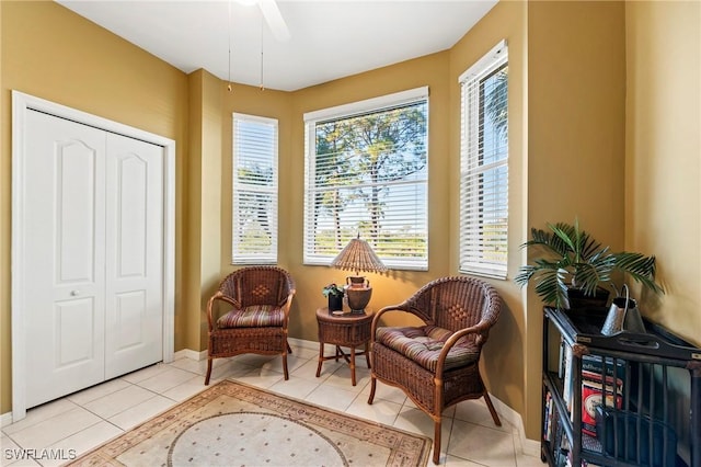 living area with a ceiling fan, light tile patterned flooring, and baseboards