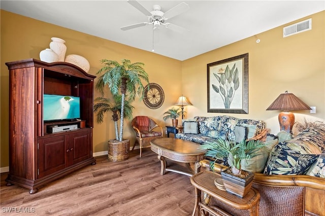 living room with light wood-style floors, visible vents, ceiling fan, and baseboards