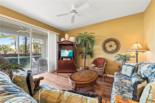 living area featuring wood finished floors, a ceiling fan, and baseboards