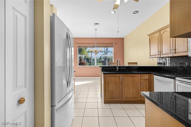 3266 Sturgeon Bay Ct, Naples, FL 34120 - kitchen with light tile patterned floors, a peninsula, a sink, freestanding refrigerator, and dishwasher