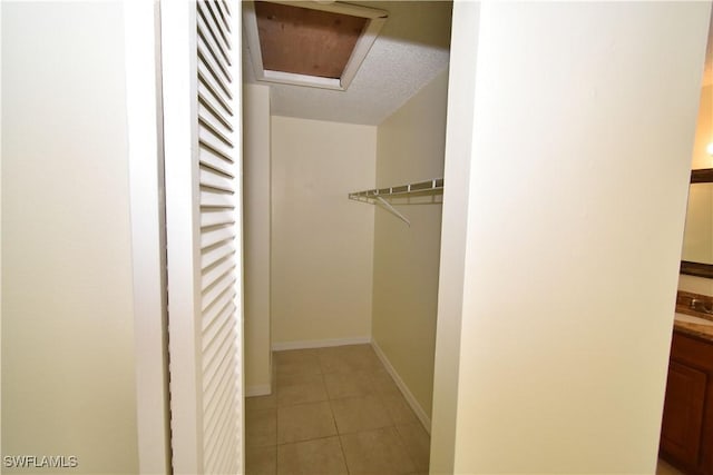 spacious closet with attic access and light tile patterned floors