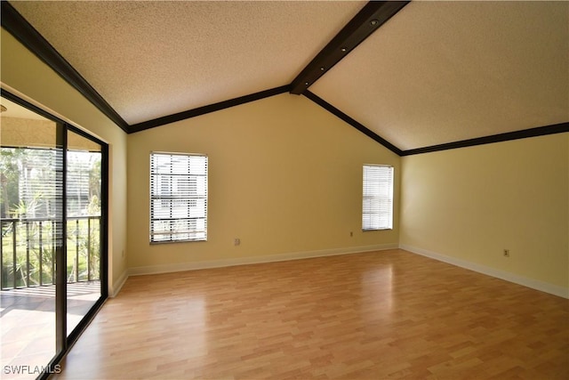 spare room with vaulted ceiling with beams, light wood-style flooring, baseboards, and a textured ceiling