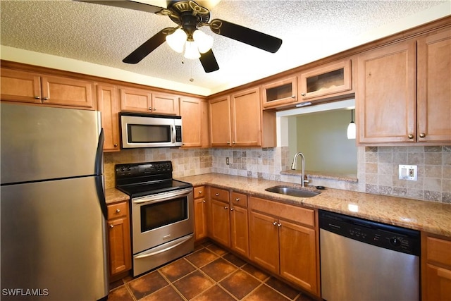 kitchen with appliances with stainless steel finishes, backsplash, a sink, and glass insert cabinets