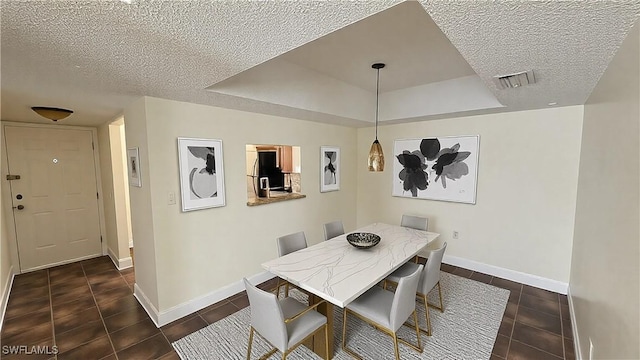 dining space with a tray ceiling, visible vents, and a textured ceiling