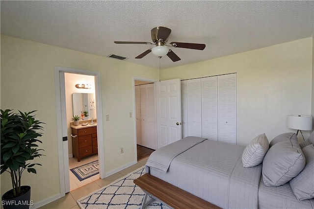 bedroom with light tile patterned floors, a textured ceiling, visible vents, a ceiling fan, and ensuite bath