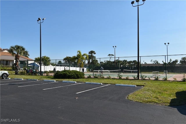 uncovered parking lot with a tennis court and fence