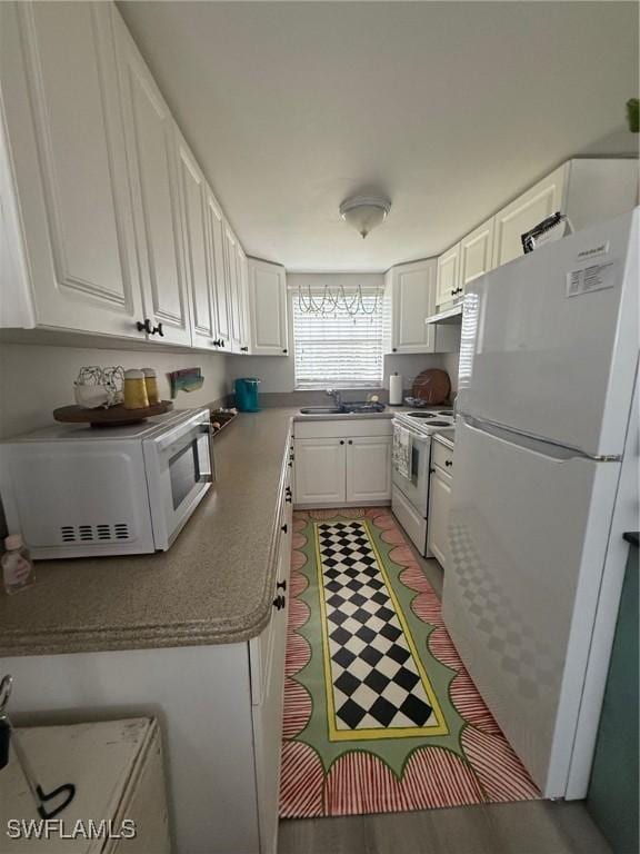 kitchen with white appliances, a sink, white cabinetry, and under cabinet range hood