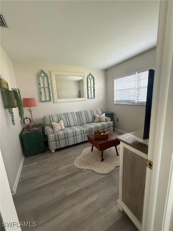 living area featuring visible vents, baseboards, and wood finished floors