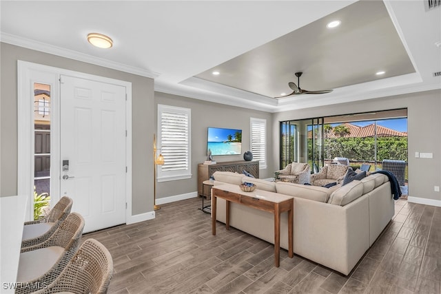 living room featuring baseboards, a tray ceiling, wood finish floors, and crown molding