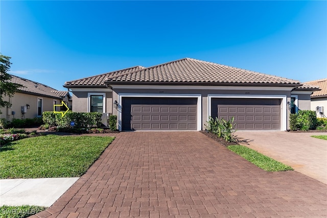 view of front of property featuring decorative driveway, a tile roof, stucco siding, an attached garage, and a front yard