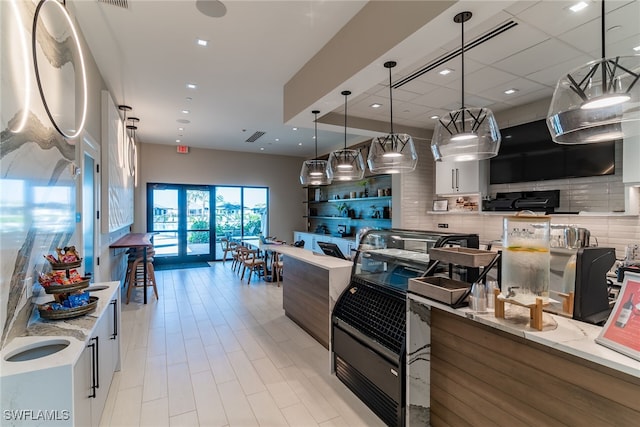 kitchen featuring open floor plan, light stone countertops, decorative light fixtures, and decorative backsplash