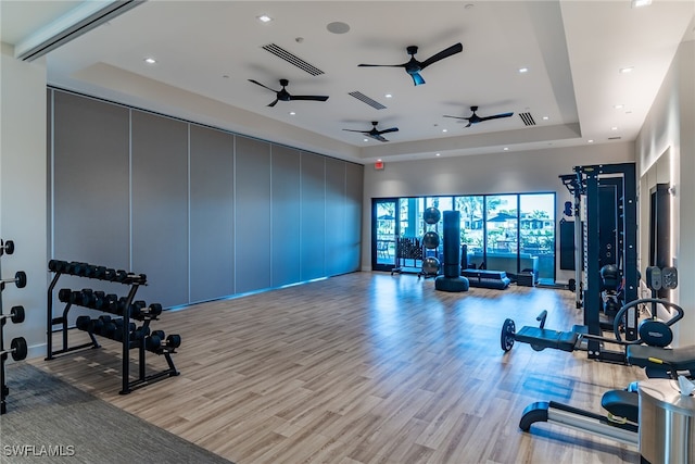 exercise room featuring visible vents, a raised ceiling, wood finished floors, and recessed lighting