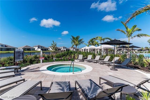 view of pool with a community hot tub, fence, and a patio