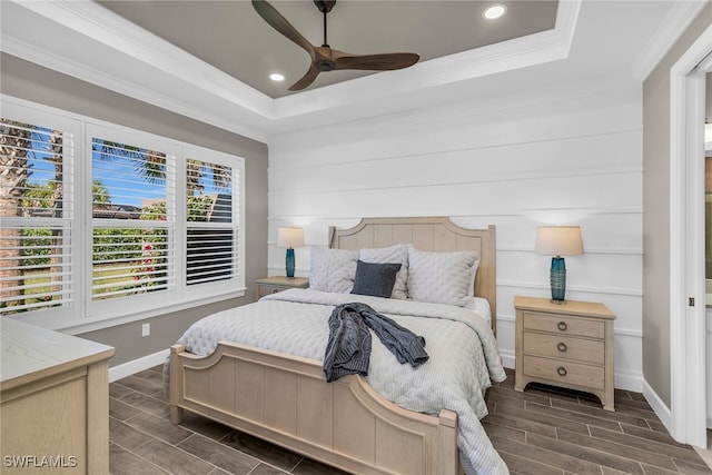 bedroom featuring wood tiled floor, baseboards, a raised ceiling, and crown molding