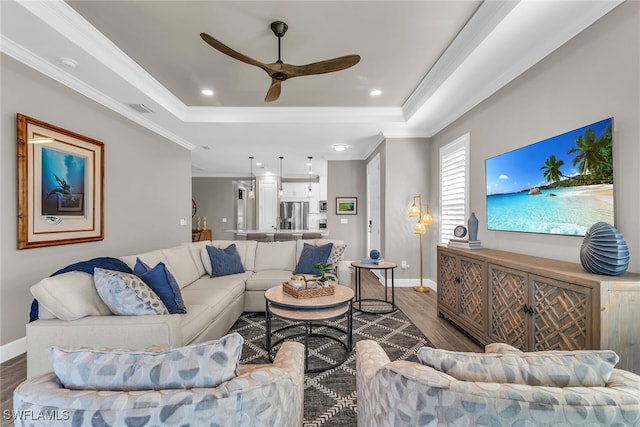 living area featuring dark wood-style floors, a tray ceiling, visible vents, and crown molding