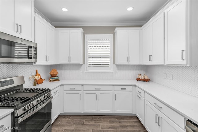 kitchen featuring appliances with stainless steel finishes, white cabinets, crown molding, and light countertops