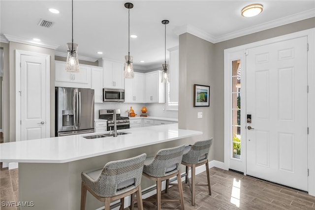 kitchen featuring visible vents, appliances with stainless steel finishes, ornamental molding, wood finish floors, and a kitchen bar