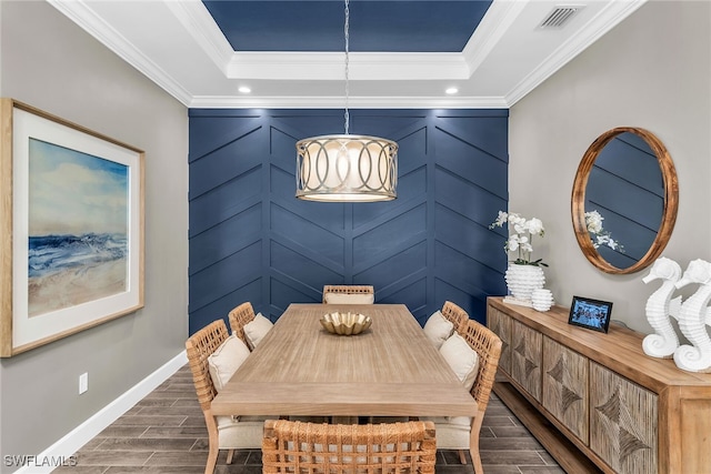 dining area with wood finish floors, crown molding, a raised ceiling, visible vents, and baseboards