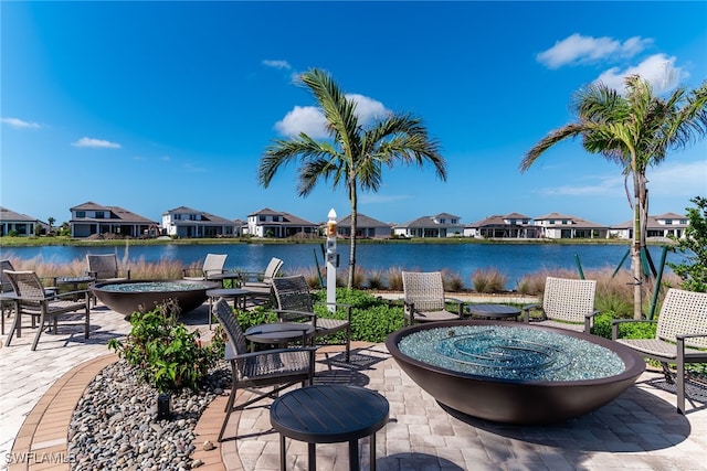 view of patio / terrace featuring a water view, an outdoor fire pit, and a residential view