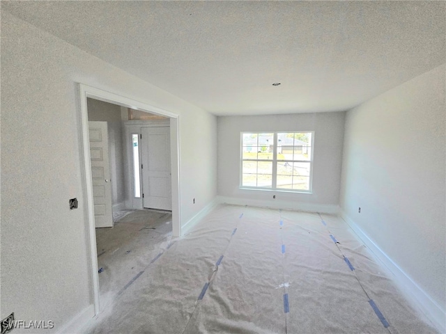 unfurnished room featuring a textured ceiling and baseboards