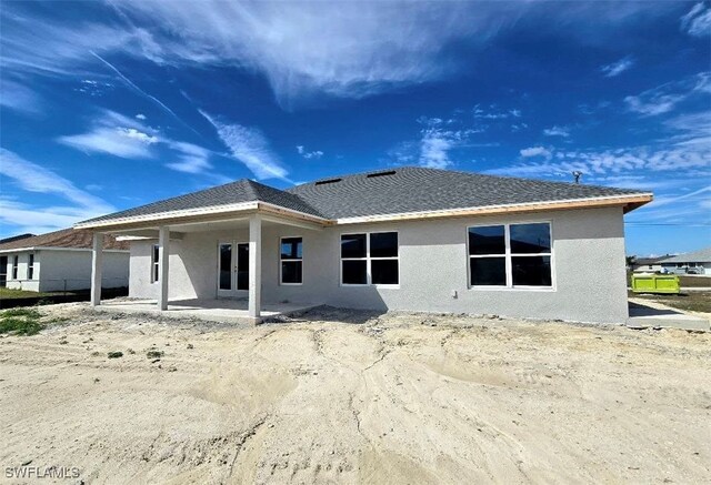 back of property with roof with shingles, a patio, and stucco siding