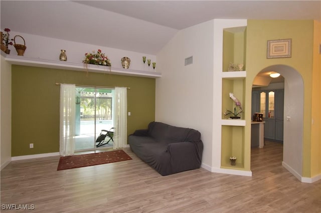 living area with arched walkways, visible vents, baseboards, and wood finished floors