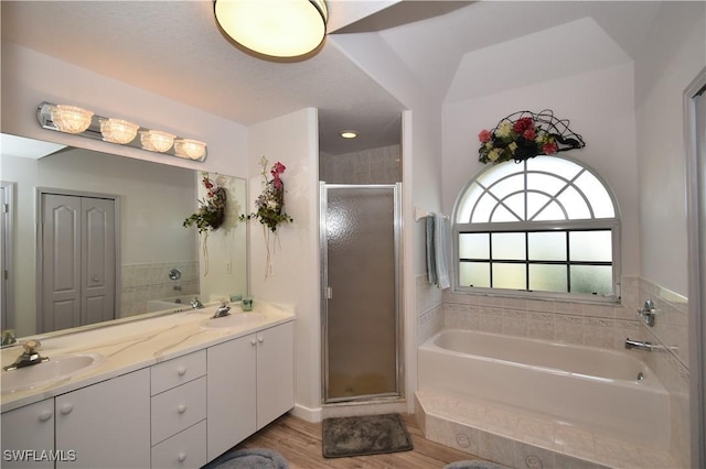 full bathroom featuring double vanity, a stall shower, a sink, and a bath