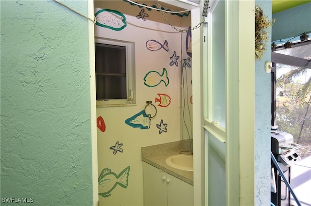 bathroom with a textured wall and vanity