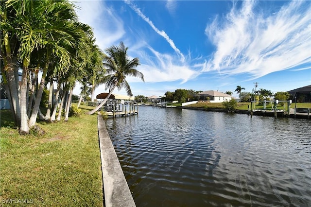 view of dock with a water view and a lawn