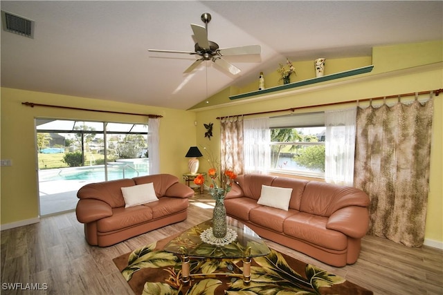 living area with visible vents, ceiling fan, vaulted ceiling, wood finished floors, and baseboards