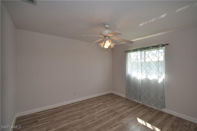 empty room with a ceiling fan, baseboards, and wood finished floors