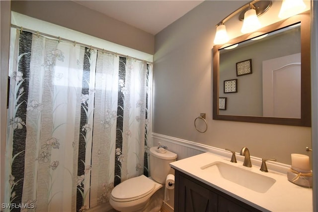 bathroom featuring a shower with curtain, a wainscoted wall, vanity, and toilet