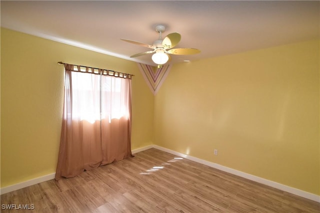 unfurnished room with wood finished floors, a ceiling fan, and baseboards