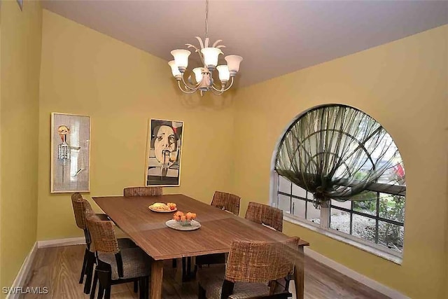 dining space featuring a chandelier, wood finished floors, and baseboards