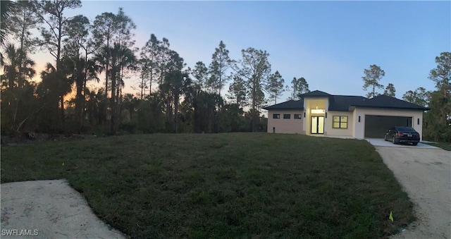 view of front of house featuring a garage, concrete driveway, and a lawn