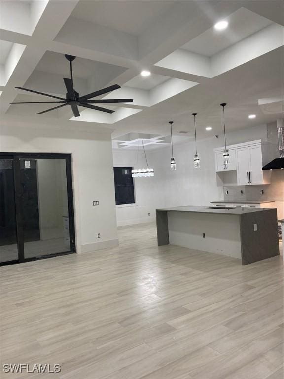 kitchen with coffered ceiling, white cabinets, a ceiling fan, light wood-style flooring, and open floor plan