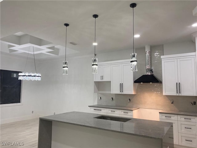 kitchen featuring tasteful backsplash, dark stone counters, white cabinets, and wall chimney range hood