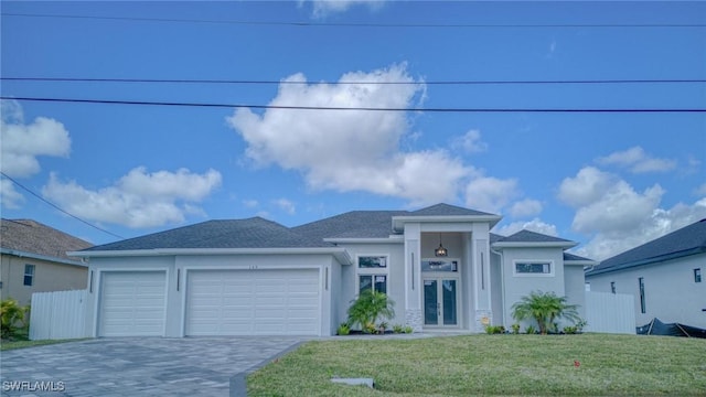 prairie-style home with decorative driveway, stucco siding, a front yard, fence, and a garage