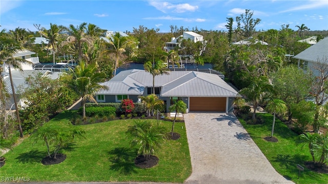 view of front facade featuring decorative driveway, an attached garage, a front lawn, and metal roof